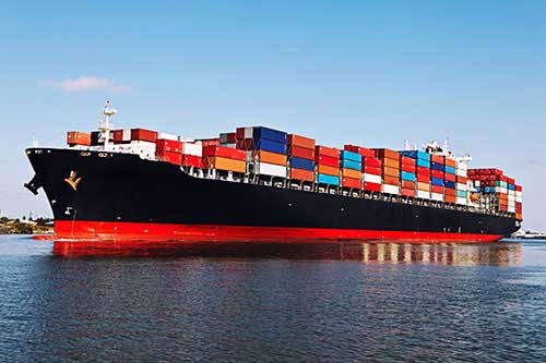 Fully loaded cargo ship with black and orange color combination running on the sea