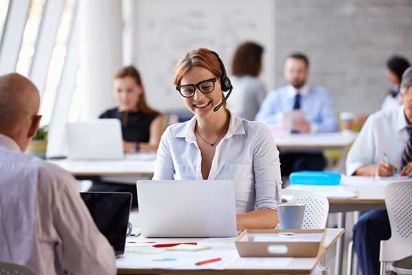 20cube Female customs clearance officer with their client through a headset by using a laptop